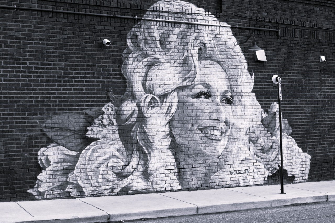 Mural of Dolly Parton painted on a brick wall.