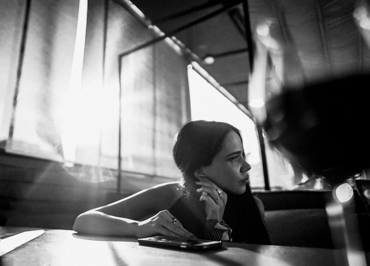 Black and white photo of a person sitting by a window, representing growth, reflection, and moving on from the past.