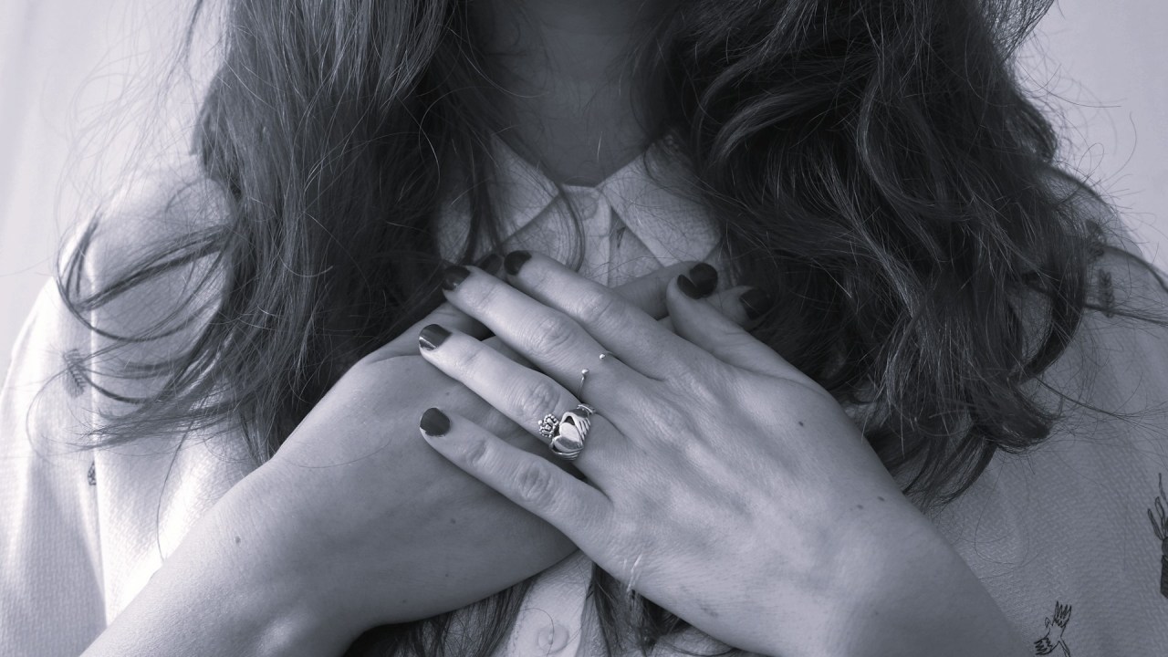 Woman holding her hands over her heart, representing self-love and choosing yourself