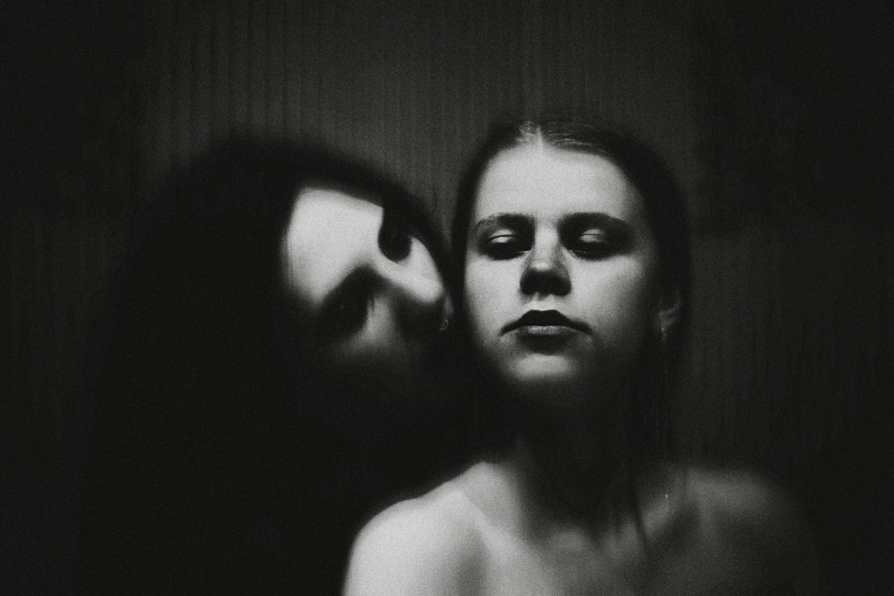 Woman with eyes closed holding her head, representing emotional pain, unanswered questions, and healing.