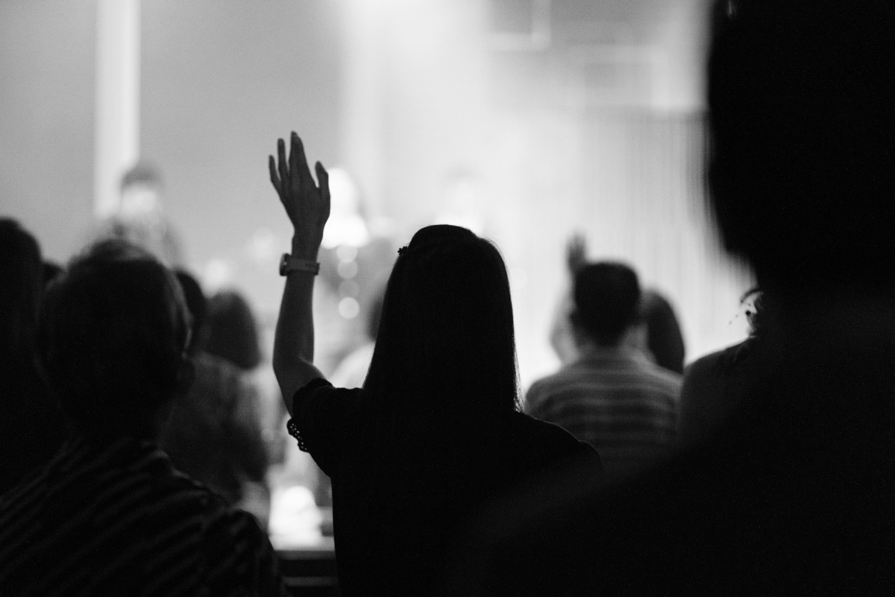 Silhouetted person raising a hand in a crowd, representing personal growth without the need for recognition or applause.