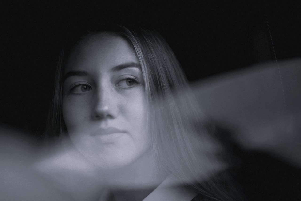 Black and white image of a woman looking at her reflection, representing personal growth, change, and evolving beyond an earlier version of yourself.