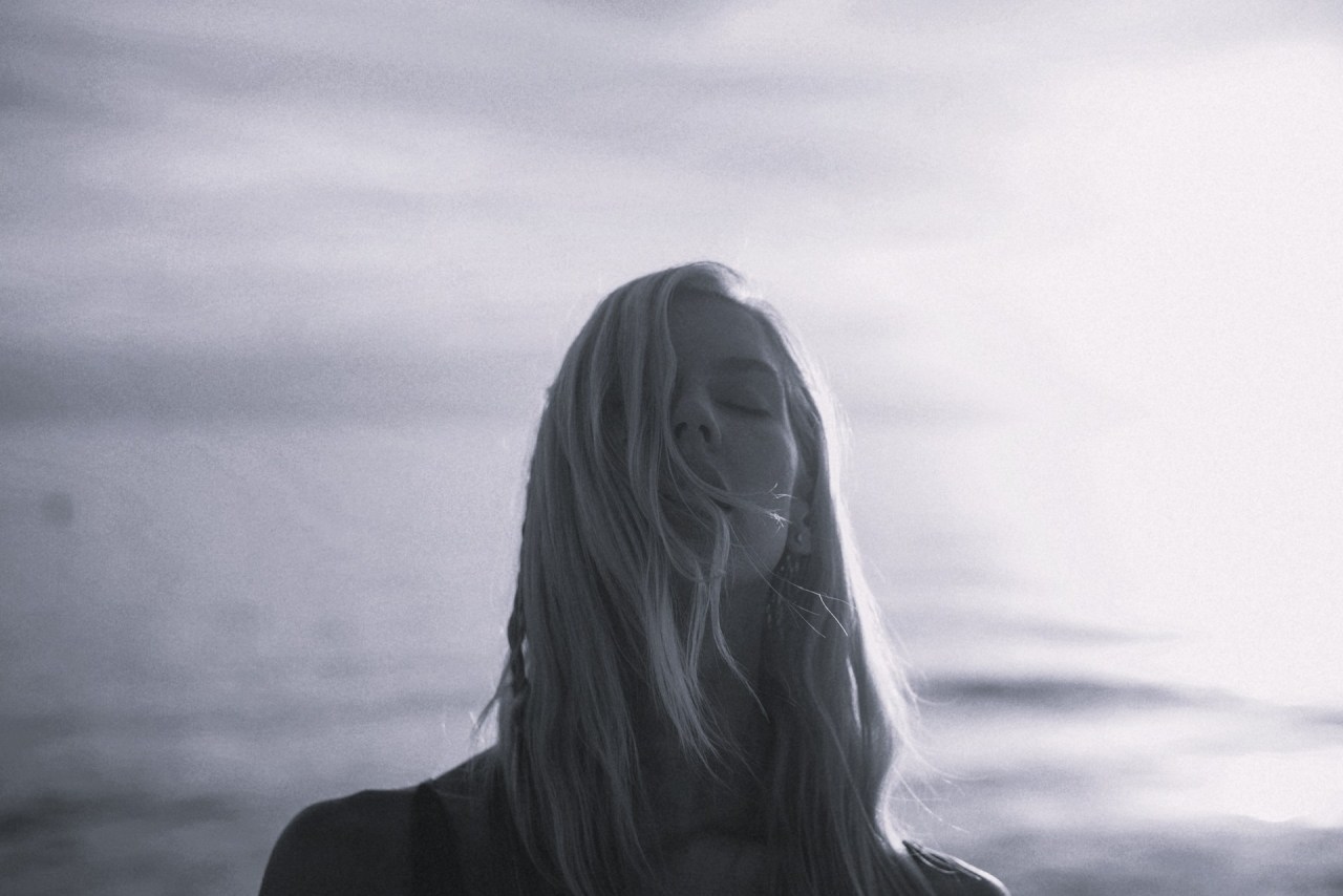 Woman looking out over the water, representing gratitude while considering a different path forward.