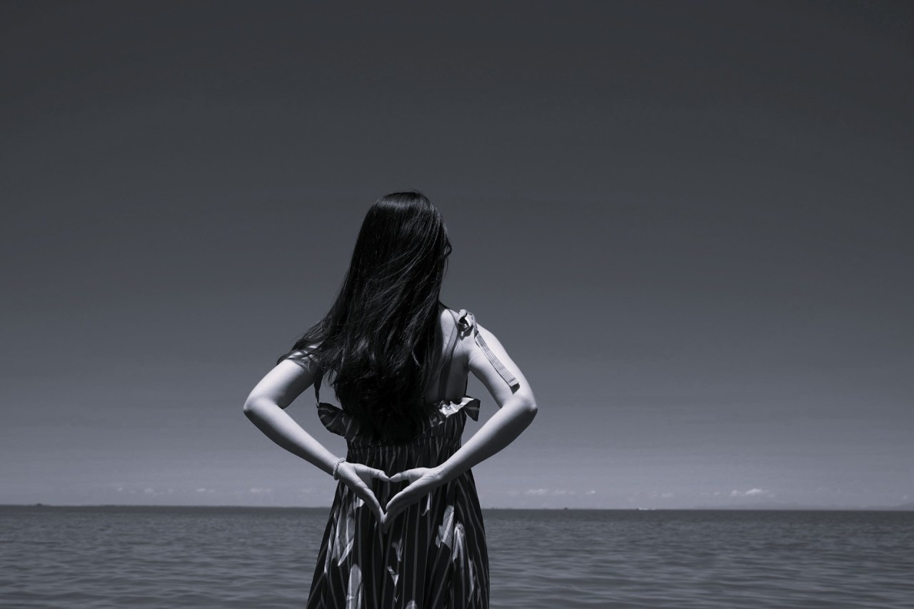 Black and white image of a woman standing alone with her back to the camera, representing self-acceptance, self-compassion, and personal growth.