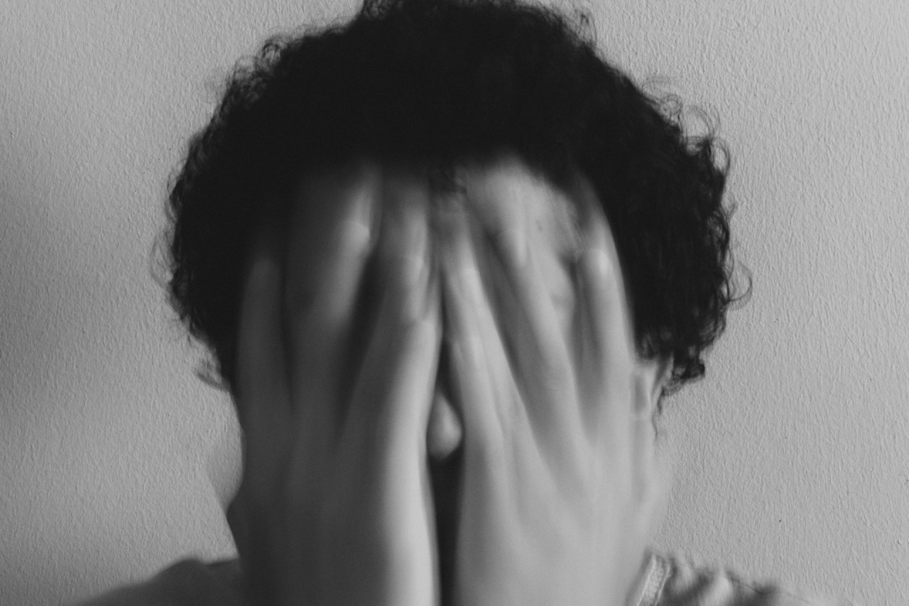 Person covering their face, representing the emotional weight of carrying responsibilities that may not belong to them