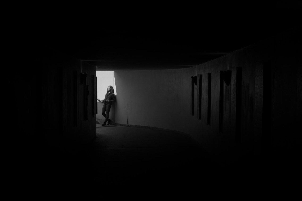 Person standing alone at the end of a dark hallway, representing the uncertainty of an ending without answers