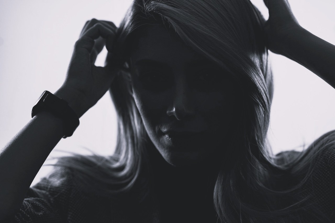 Black-and-white photograph of a woman holding her hands to her head, expressing stress and uncertainty.