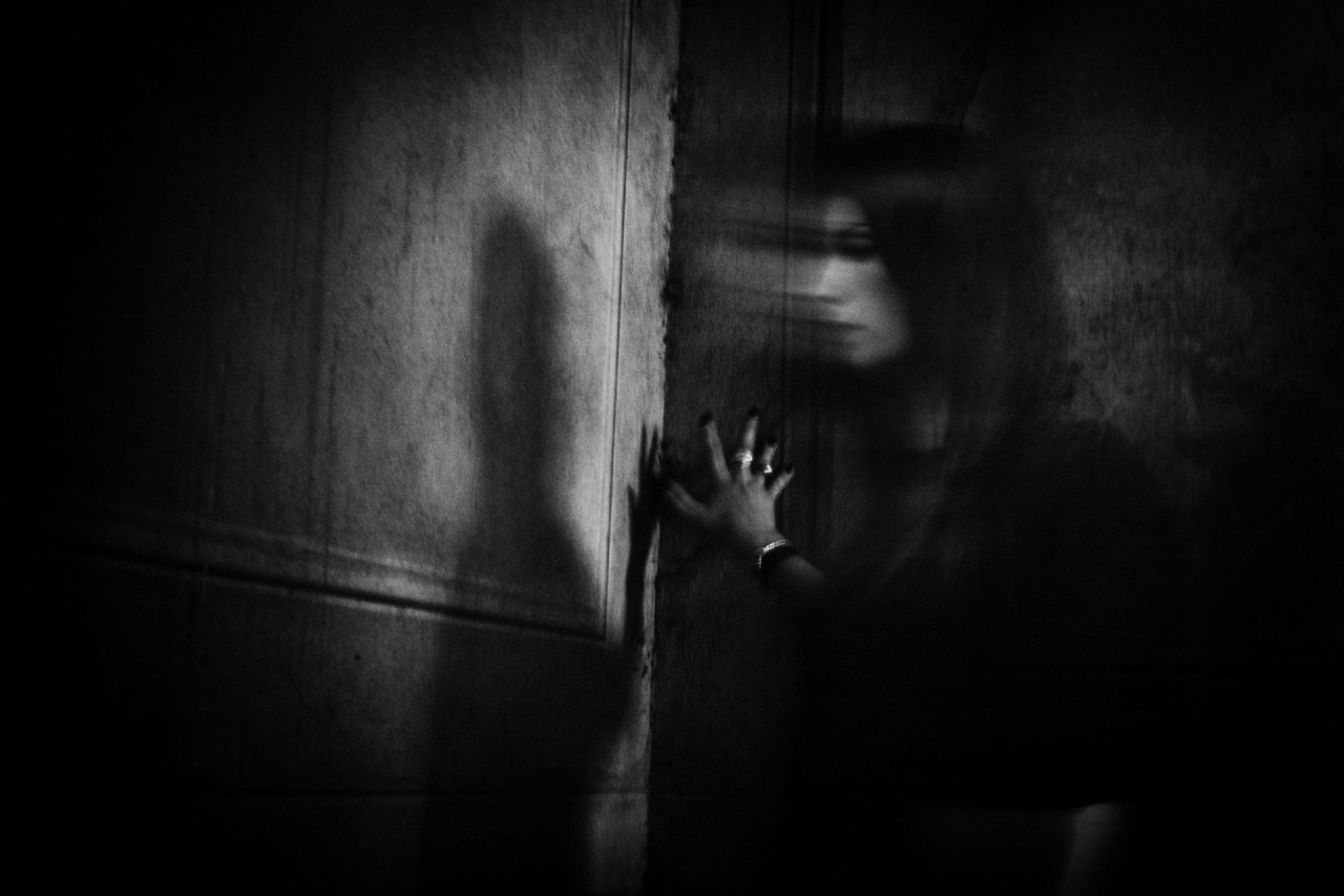 Woman standing alone in a dark room, representing the loneliness and self-abandonment that can come from waiting to be chosen