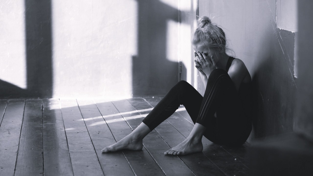 Woman sitting by a window resting, representing the importance of taking time to rest before reaching exhaustion